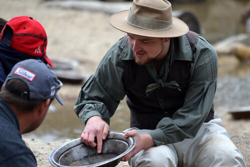 Man showing two other people gold found in river with silver panning bowl