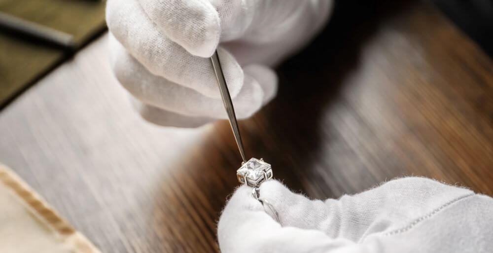 Jeweler with gloves on repairing diamond ring. Image of jewelry repair in Westmont
