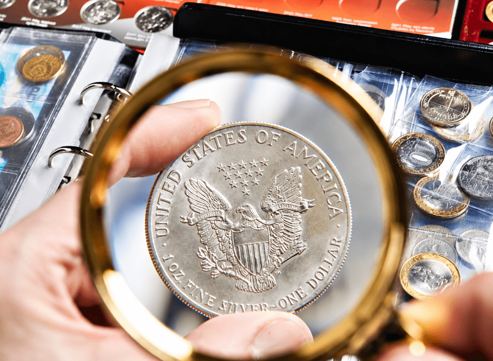 Magnifying glass inspecting silver coin in collection binder