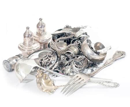 Pile of silver flatware and jewelry on white background